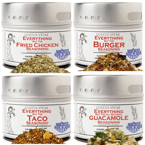 Four tins from Gustus Vitae’s Everything but the Classic Cookout set—Burger, Taco, Guacamole Seasoning, and Everything But The Fried Chicken—are shown with piles of their all-natural handcrafted spice blends in front.