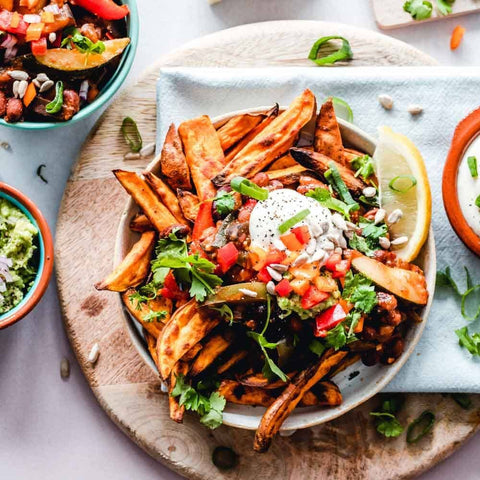 Enjoy sweet potato fries seasoned with Gustus Vitaes Everything but the Fajita Night Collection, topped with sour cream, tomatoes, bell peppers, sunflower seeds, fresh herbs, and a lemon wedge—perfect with dips and veggies.