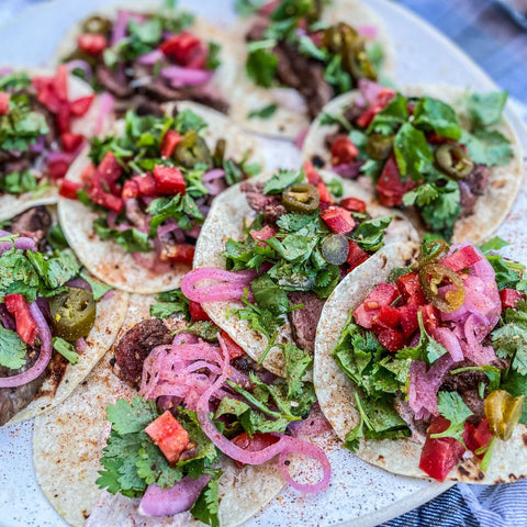 Enjoy a plate of small beef tacos with pickled red onions, jalapeños, tomatoes, cilantro, and lettuce on corn tortillas, all seasoned with the Gustus Vitae Meal Prep Flavor Combo Set - 4 Pack for gourmet flavor in every bite.