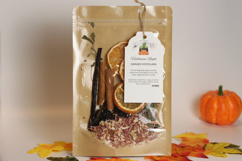 Forev'Herbs Halloween Night Simmer Potpourri features dried citrus, autumn spices, and flowers in a labeled pouch tied with string. Autumn leaves and a mini pumpkin are pictured in the background.
