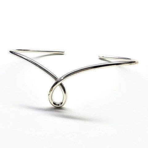 The Timeless Classic Silver Reversible Teardrop Awareness Bangle by Alexa Martha Designs, with a minimalist open design and central loop, rests on a white background—evoking the look of a sleek sterling silver bangle.