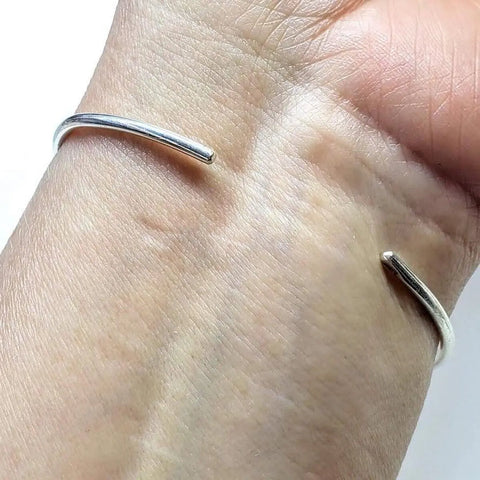 The Timeless Classic Silver Reversible Teardrop Awareness Bangle by Alexa Martha Designs features a minimalist sterling silver open-ended design with smooth, rounded ends, showcasing the elegance of handcrafted jewelry.