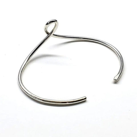 The Timeless Classic Silver Reversible Teardrop Awareness Bangle by Alexa Martha Designs features a sleek open design with looped end and curved band—a perfect handcrafted piece, shown on a white background.