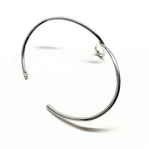 The Timeless Classic Silver Reversible Teardrop Awareness Bangle by Alexa Martha Designs is a handcrafted minimalist sterling silver piece, featuring a single teardrop accent, displayed on a white background.