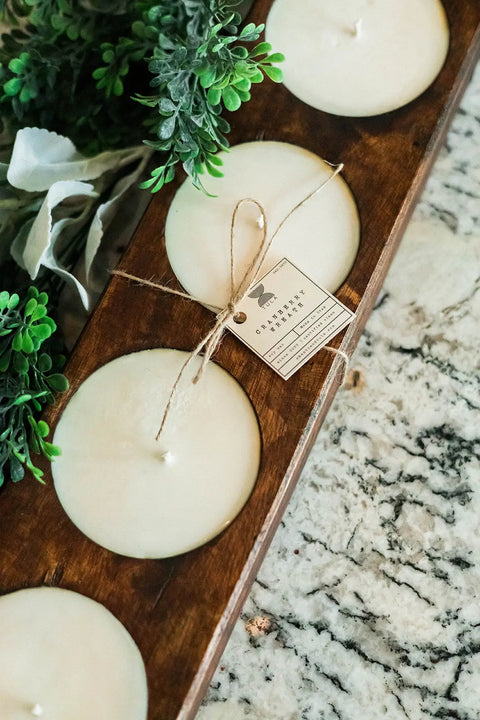 The Shanti + Tula Handcrafted 5-Hole Cheese Mold Candle—an elegant 28 soy dough bowl centerpiece—is displayed on a marbled countertop, accented by green leafy decor.