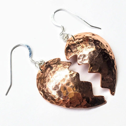 The Broken Heart Earrings from Sculpted Copper by Alexa Martha Designs feature two jagged half-heart shapes joined by silver hooks, creating an artistic accent for any look.