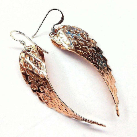 The Copper Hammer Pattern Sculpted Angel Wings Earrings by Alexa Martha Designs feature a handcrafted, metallic scale-like texture with a shiny, reflective gold and silver finish.