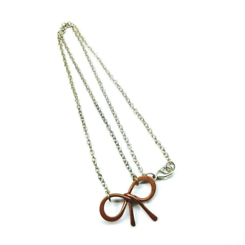 The Wire Wrapped Copper Bow Tie Silver Chain Necklace by Alexa Martha Designs features a handcrafted copper bow tie pendant on a sterling silver chain, shown against a white background.