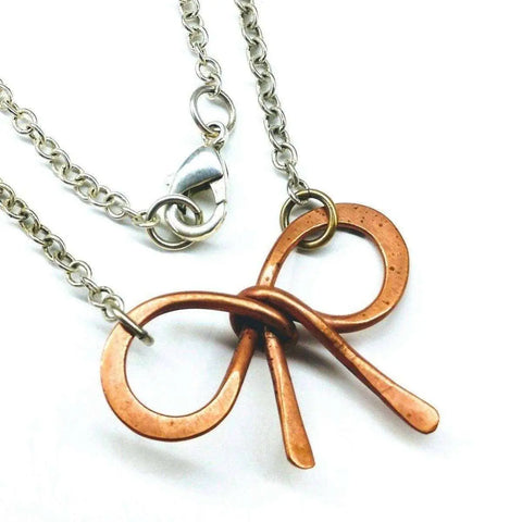 The Wire Wrapped Copper Bow Tie Silver Chain Necklace by Alexa Martha Designs features a handcrafted copper bow tie pendant on a sterling silver chain with a lobster clasp for an elegant finish.