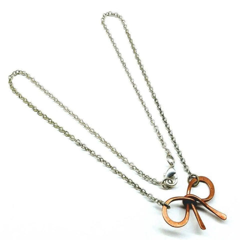 The Wire Wrapped Copper Bow Tie Silver Chain Necklace by Alexa Martha Designs showcases a copper bow tie pendant on a sterling silver chain, presented against a white background.