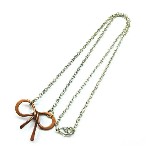 The Alexa Martha Designs Wire Wrapped Copper Bow Tie Silver Chain Necklace showcases a copper bow pendant on a silver chain, adding a playful touch.
