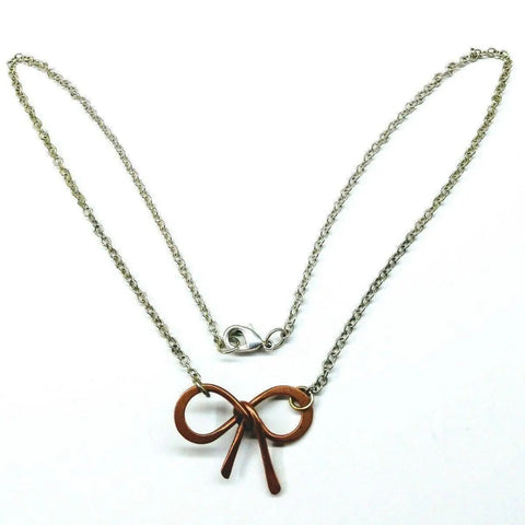 The Alexa Martha Designs Wire Wrapped Copper Bow Tie Silver Chain Necklace is elegantly displayed on a white background.