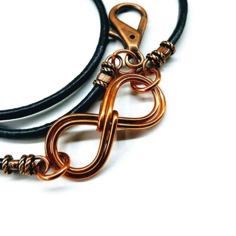 The Copper Double Infinity Gender Neutral Leather Wrap Bracelet by Alexa Martha Designs features black leather, copper infinity symbols, and a sturdy clasp—a stylish unisex accessory.