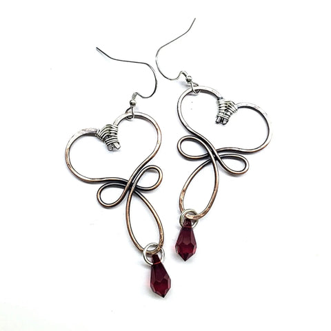 Crystal Drop Copper Heart Earrings by Alexa Martha Designs feature wire-formed heart shapes and a small red teardrop bead, shown on a white background.