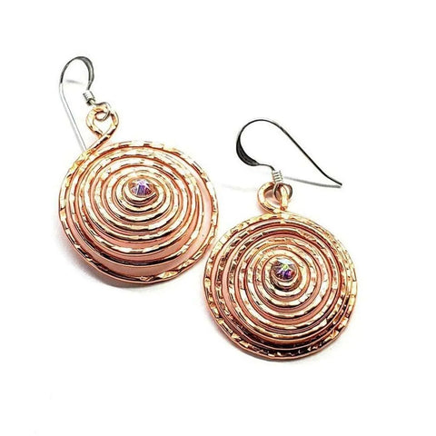 Alexa Martha Designs Crystal Embedded Copper Spiral Hoop Earrings feature handmade copper spirals with hook closures and a sparkling crystal set at the center of each textured hoop.