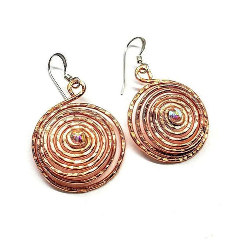 Crystal Embedded Copper Spiral Hoop Earrings by Alexa Martha Designs feature handmade copper spirals with a small iridescent gem at the center of each, shown on a white background.