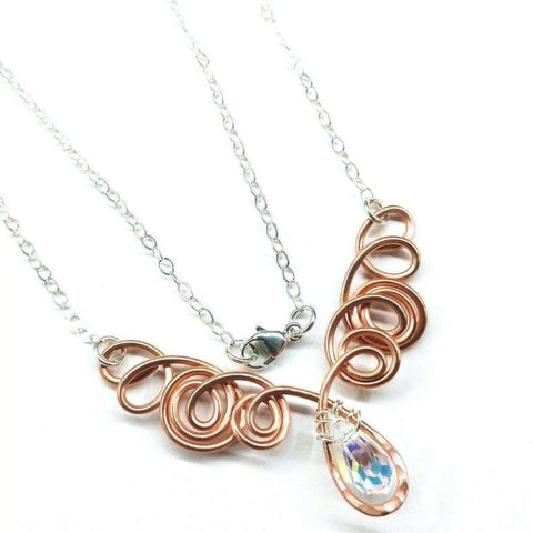 The Copper Wire Sculpted Angel in Flight Necklace by Alexa Martha Designs features a sterling silver chain and a swirled copper wire pendant with a teardrop Swarovski crystal—an elegant, unique accessory for any occasion.