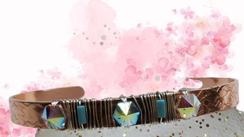 The Crystal Spike Bead Copper Cuff by Alexa Martha Designs is a punk-inspired copper bangle with textured patterns, wire wrapping, iridescent Swarovski crystals, turquoise stones, and pink watercolor flower accents.