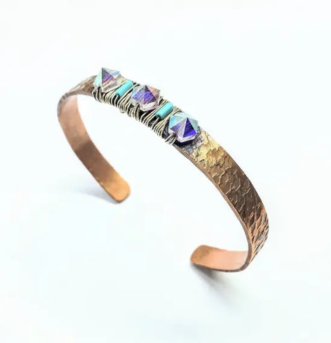 The Crystal Spike Bead Copper Cuff by Alexa Martha Designs is a hammered copper bracelet with three iridescent Swarovski pyramid beads and turquoise accents, shown on a white background.
