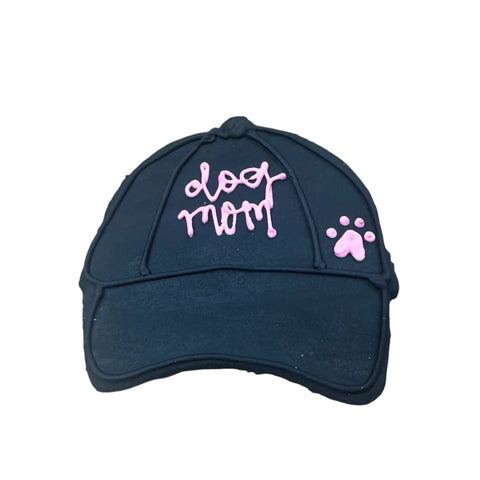 Dogtown Bakerys Dog Mom Hat Cookie is a black baseball cap-shaped treat decorated with “dog mom” and a pink paw print in icing—a charming artisan pet-themed gift.