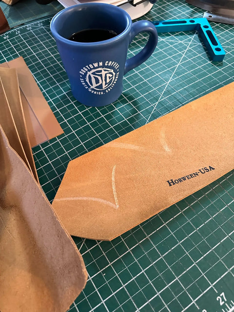 A blue coffee mug sits on a green cutting mat beside tan Horween English Bridle Leather, branded HORWEEN-USA, and chalk lines—a Sully + Proper Supply Utility Pouch leatherworking project in progress.