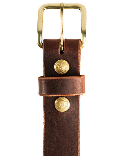 A close-up of Homestead Brand’s Essential Leather Belt No. 1508, made in the USA with brown leather, a solid brass buckle, two gold rivets, visible stitching, and a textured finish.