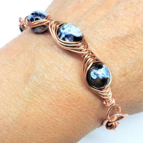 The handmade Herringbone Wire Wrap Child Abuse Prevention Half Cuff Ribbon Bracelet by Alexa Martha Designs features intricate copper loops, marbled beads, and a unique herringbone design for an elegant Southwestern look.