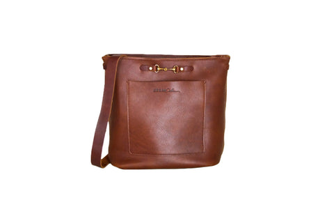 The Lexington Julep by Urban Southern is a brown leather crossbody with an external front pocket, gold-tone buckle detail, and adjustable strap, shown on a white background. This equestrian handbag lends timeless style to any outfit.