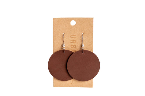 Urban Southern Everyday Earrings: round brown leather earrings with bronze-plated hooks, displayed on a light brown card. Lightweight for comfortable daily wear.