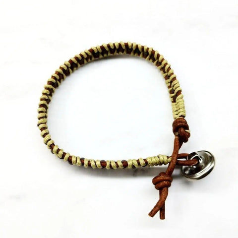 The Leather Seed Bead Rattlesnake Tail Weave Bracelet by Alexa Martha Designs features tan and brown woven cords with a tied loop and round metallic button clasp, shown on a white background.
