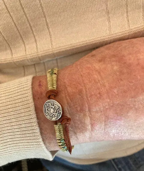 A close-up of a persons wrist wearing the Leather Seed Bead Rattlesnake Tail Weave Bracelet by Alexa Martha Designs, paired with a beige ribbed long-sleeve sweater.