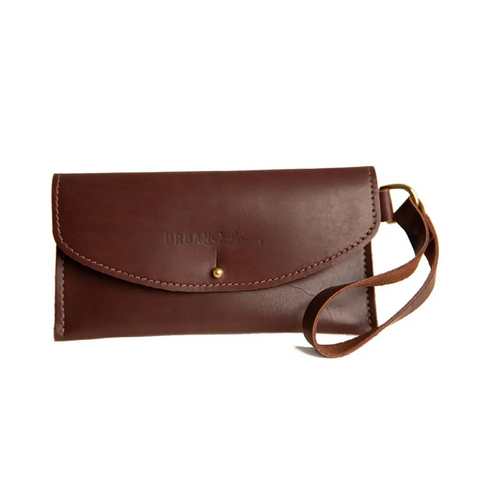 The Ruby Wristlet Wallet by Urban Southern is a brown full-grain leather wallet with a wrist strap and button closure, handcrafted in the USA and featuring the embossed Urban Southern name on the front.