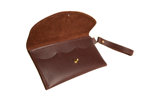 The Ruby Wristlet Wallet by Urban Southern is a handcrafted full-grain leather wallet in brown, made in the USA. It features a wrist strap, multiple card slots, and a button closure, shown on a white background.