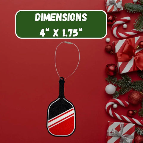 The Chatelet Manufacturing Pickleball Paddle Christmas Ornament, made in the USA, features red, black, and white stripes. Measuring 4” x 1.75”, it’s the perfect holiday gift for pickleball fans! Shown on a red background with festive décor.