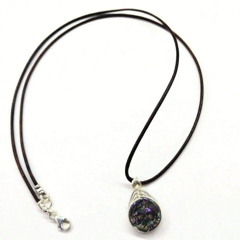 The Wire Wrapped Rainbow Druzy Necklace by Alexa Martha Designs features a teardrop Titanium Druzy Agate pendant with purple and green hues, wrapped in herringbone wire on a black cord with silver clasp for an elegant touch.