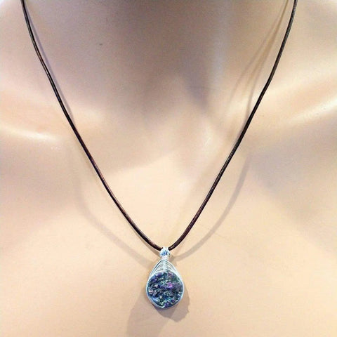 The Wire Wrapped Rainbow Druzy Necklace by Alexa Martha Designs features a multicolored druzy stone pendant on a black cord, beautifully displayed on a mannequin bust.