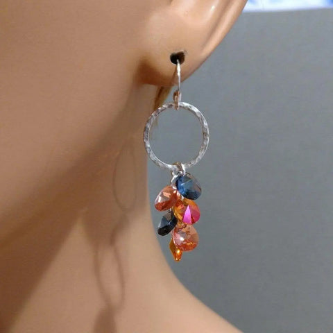 Close-up of an earlobe wearing Alexa Martha Designs Silver Circle Multi Color Crystal Drop Dangle Earrings, featuring blue, pink, and orange teardrop beads.