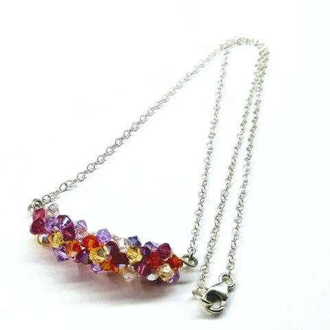 The Silver Multi Color Spring Blossom Crystal Necklace by Alexa Martha Designs features a sterling silver chain with a cluster of faceted red, purple, yellow, and clear beads. This handmade piece is shown on a white background with its clasp visible.