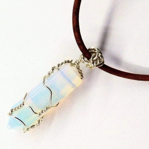 The Silver Wire Wrapped Gemstone Crystal Point Pendant by Alexa Martha Designs features an iridescent opalite stone wrapped in sterling silver, hanging from a brown leather necklace and displayed against a white background.