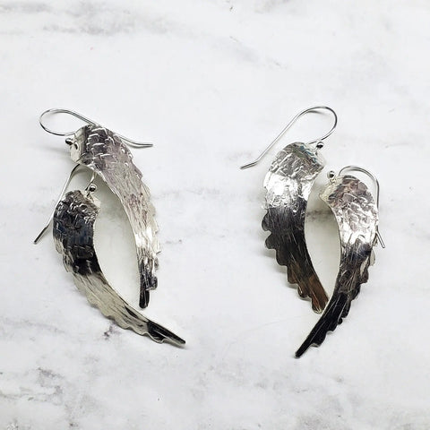 Sterling Silver Hammer Pattern Sculpted Angel Wing Earrings by Alexa Martha Designs, displayed on white marble—a stunning piece of handmade jewelry.