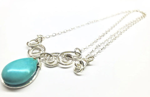The As Seen on TV Turquoise Drop Sterling Silver Wire Wrapped Necklace by Alexa Martha Designs features an ornate wire-swirl design and a large teardrop turquoise pendant, elegantly showcased on a white background.