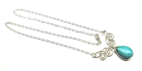The Alexa Martha Designs As Seen on TV Turquoise Drop Sterling Silver Wire Wrapped Necklace features a teardrop turquoise pendant and intricate silver swirls, beautifully showcased as a Montana made jewelry piece.