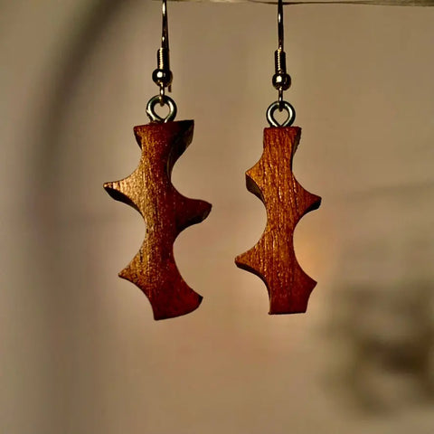 The Thorn Earring by Shop Cat Woodworks: handcrafted walnut wood earrings with a unique abstract shape and three indented curves on each side, hanging from simple metal hooks.