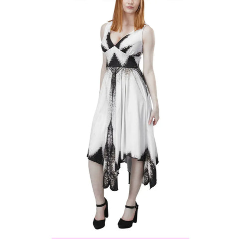 A woman with straight auburn hair models the Spiritex Large White Butterfly Dress, a sleeveless black and white asymmetrical V-neck style, paired with black heels, standing against a plain white background.