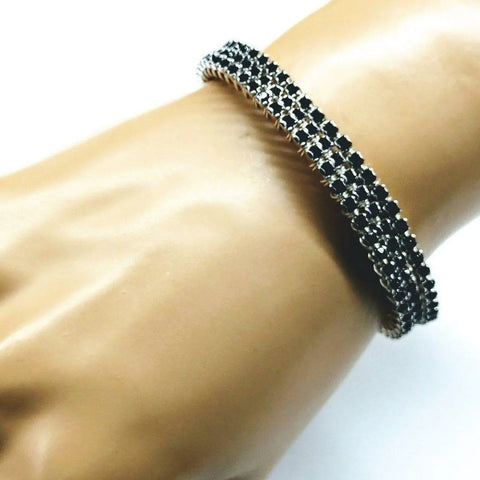 A close-up of a mannequin hand wearing the Wire Wrapped Copper Silver Black Crystal Rhinestone Bangle by Alexa Martha Designs, featuring jet black and clear rhinestones on a silver band, displayed against a plain white background.