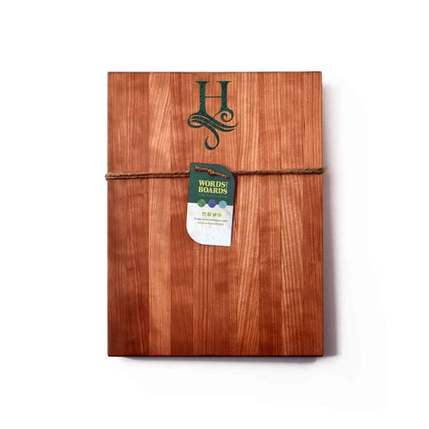 A handcrafted wooden cutting board by Words with Boards, made in the USA, features a green monogram with stone inlay—a unique personalized gift for any occasion.