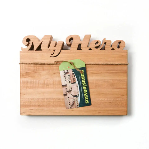 The Handcrafted Wooden Personalized Cutting Board (Small) by Words with Boards features a decorative My Hero sign, rope accent, and branded tag—perfect as a unique gift or stylish kitchen accessory. Made in the USA.