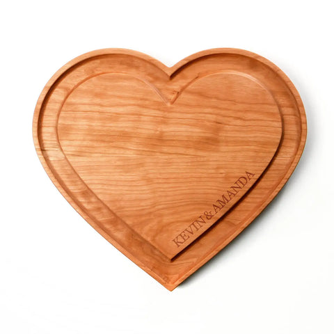 The Handcrafted Heart Shaped Wooden Cheese Board by Words with Boards is made in the USA and features a groove edge, cherry wood construction, and engraved KEVIN & AMANDA—perfect as a serving tray for cheese or charcuterie.