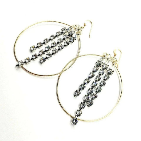 Alexa Martha Designs’ Golden Oval Hoop Crystal Chain Earrings feature three vertical strands of sparkling crystals in each golden hoop, creating stunning dangle earrings shown on a white background.