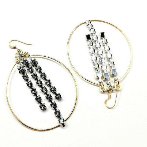 The Golden Oval Hoop Crystal Chain Earrings by Alexa Martha Designs are large gold hoops with three vertical rows of square black and silver rhinestones, creating a sparkling, eye-catching look. Shown on a white background.